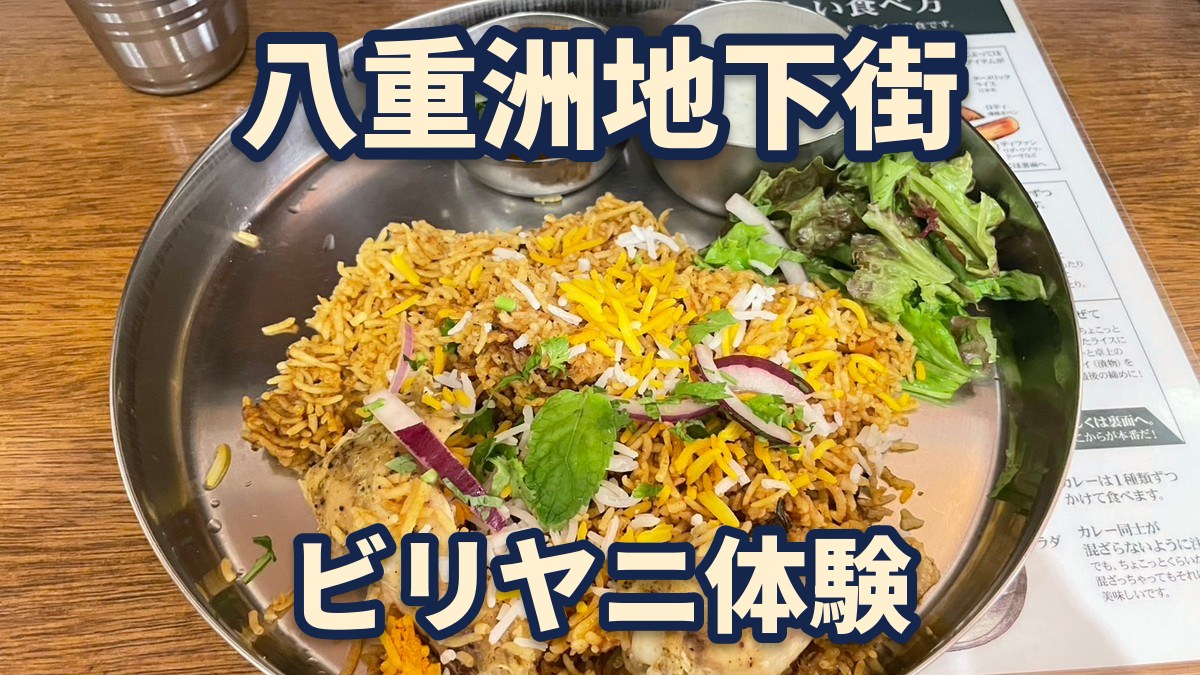 八重洲地下街のエリックサウス八重洲店のチキンビリヤニ。金属の大きな皿に、スパイスで色づいたごはんとチキン、カレーとヨーグルトのソース、サラダがのっている(筆者撮影)